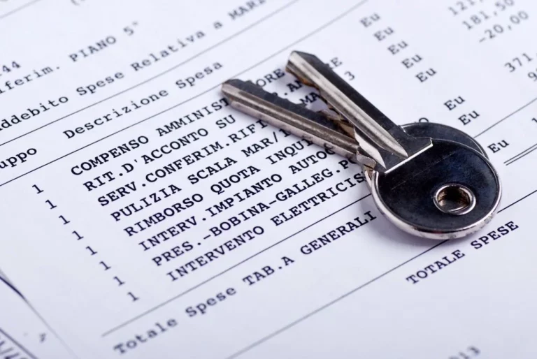 Due chiavi in metallo appoggiate su un prospetto di spese condominiali con voci come pulizia scala e compenso amministratore